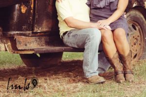 man and woman in cowboy boots engagement photo on vintage truck