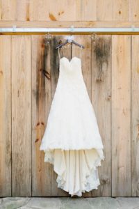 vintage wedding dress hanging in rustic barn