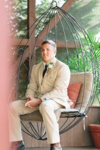 groom sitting in rustic swing