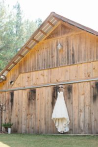 vintage wedding dress hanging on rustic barn