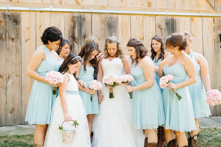 bride with bridesmaids in front of rustic barn