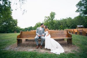 bride and groom kissing on bench at vintage wedding venue in georgia