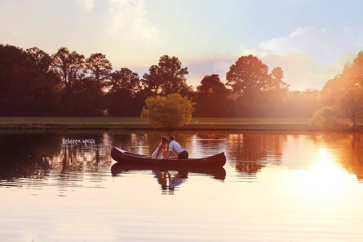 bride and groom kissing in canoe on lake