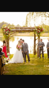 bride and groom kissing in front of Custom wedding arch at vintage wedding venue in Georgia